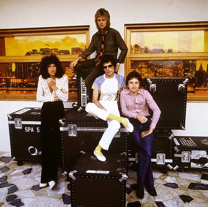 Grupės „Queen“ nariai ilsisi ant savo instrumentų dėžių. Nuotrauka daryta aštuntajame dešimtmetyje, maždaug tuo metu, kai jie įrašinėjo albumą „Jazz“.