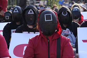 „Squid Game“ tematika proteste Pietų Korėjoje „Squid Game“ tematika proteste Pietų Korėjoje