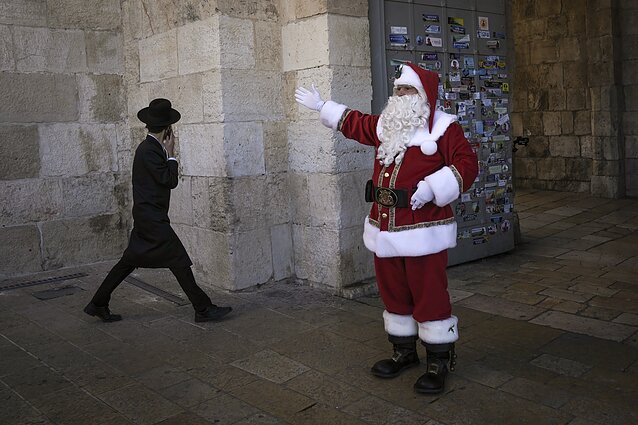 Palestinos ambasadorius prie Šventojo Sosto Issa Kassissieh, apsirengęs Kalėdų Seneliu, mojuoja praeiviams Jeruzalėje, 2024 m. gruodžio 19 d. 