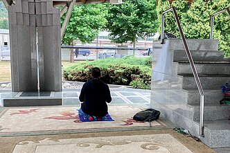 Apžiūrėjęs Srebrenicos memorialą, turistas atsiklaupia pasimelsti Apžiūrėjęs Srebrenicos memorialą, turistas atsiklaupia pasimelsti