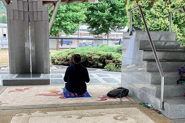 Apžiūrėjęs Srebrenicos memorialą, turistas atsiklaupia pasimelsti Apžiūrėjęs Srebrenicos memorialą, turistas atsiklaupia pasimelsti