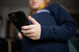 Vaikas su mobiliuoju telefonu