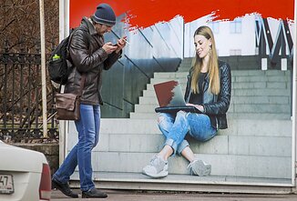 Vyras Sankt Peterburge eina pro stendą, reklamuojantį interneto paslaugas