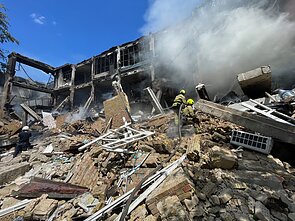 Senelis su anūku žiūri, kaip gelbėtojai ieško subombarduotos spaustuvės griuvėsiuose žmonių